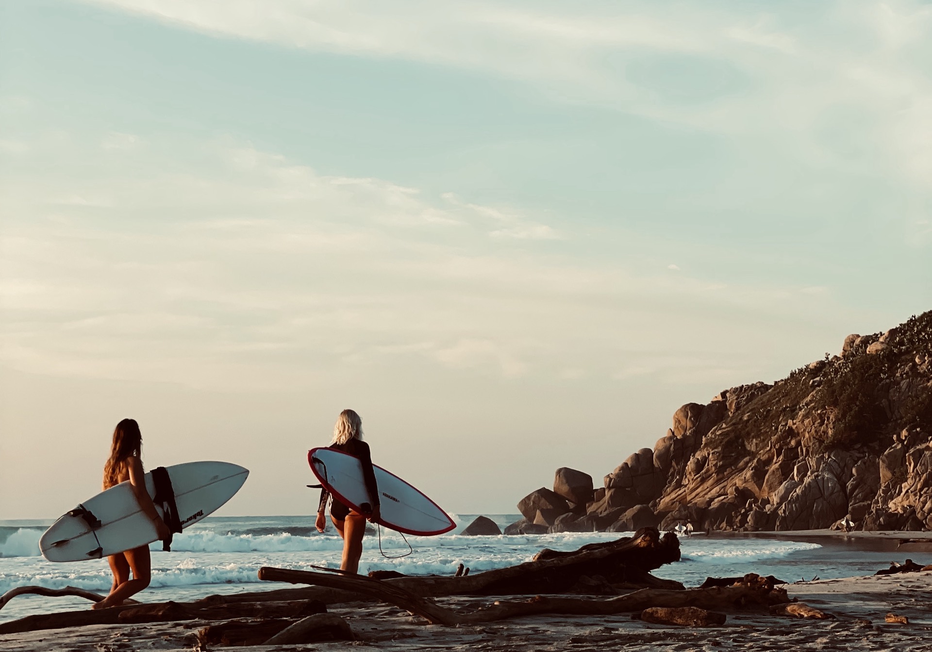 Two surfers walking to the water at a surf destination at sunset